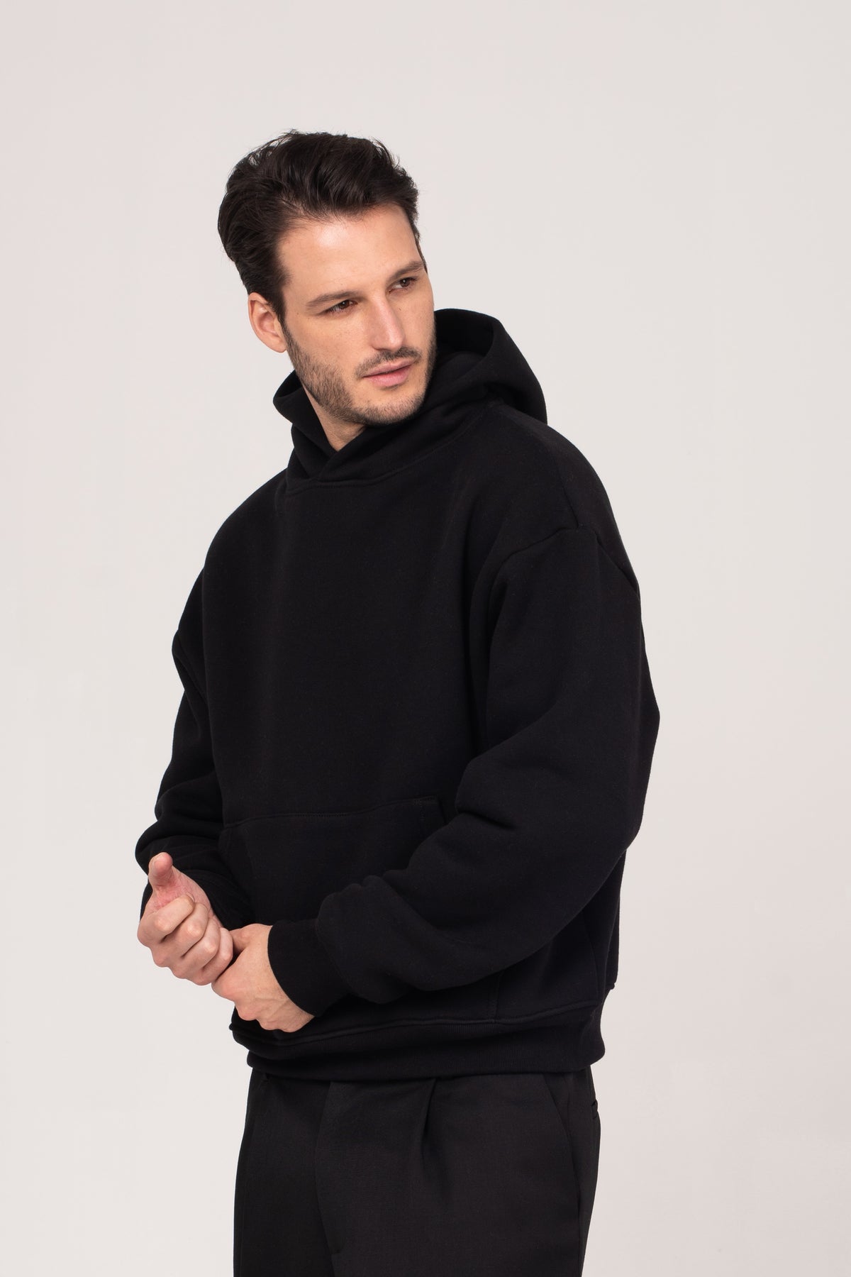 A close-up of the NO.29 men's heavyweight black hoodie, styled with black NO.29 pleated trousers. Designed with a relaxed fit and premium fabric, offering timeless style and elevated comfort.