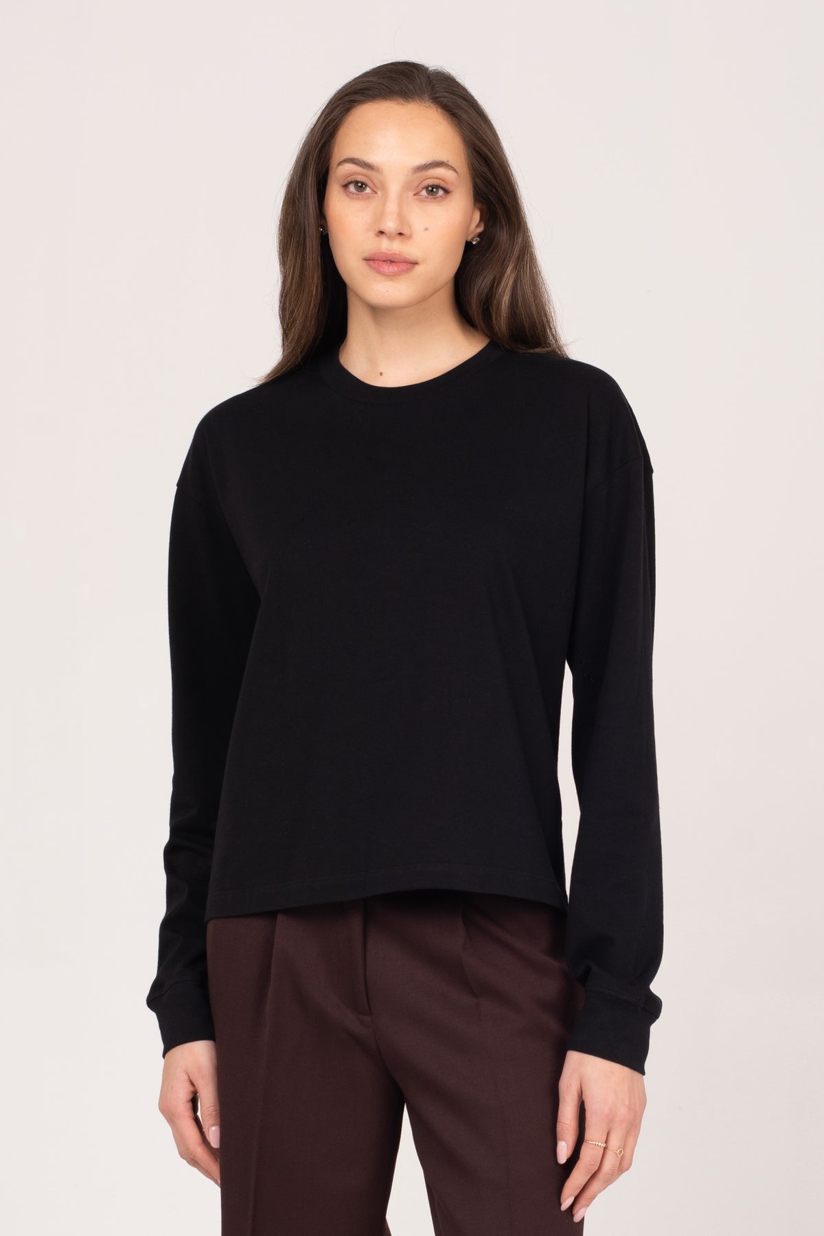 A close-up of the NO.29 women's black long sleeve shirt, styled with brown NO.29 pleated trousers. A refined, minimalist essential designed for everyday wear and effortless elegance.